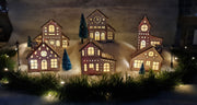 A picturesque scene of wooden Christmas houses adorned with vibrant lights, creating a festive and cheerful atmosphere.