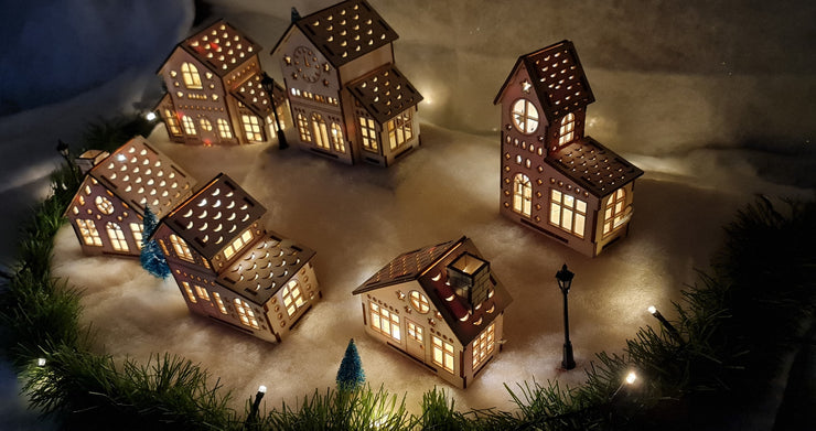 A picturesque scene of wooden Christmas houses adorned with vibrant lights, creating a festive and cheerful atmosphere.